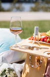 Folding picnic table with a bottle of rose and wine glass with fruit platter.